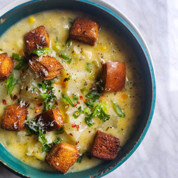 Potato chowder served in a beautiful blue bowl, topped with crispy croutons.