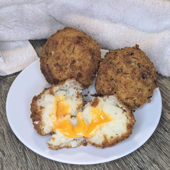 Three potato bombs on a plate. One is cut open to show the cheesy center.