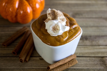pumpkin spice pudding with cool whip in a white bowl on a wood table top.