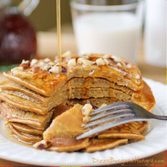 Side close up shot of pumpkin pancakes stacked on each other with a fork taking slices out.