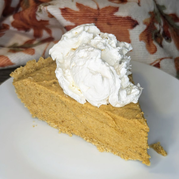 A slice of pumpkin chiffon pie with a scoop of whipped cream on top. 