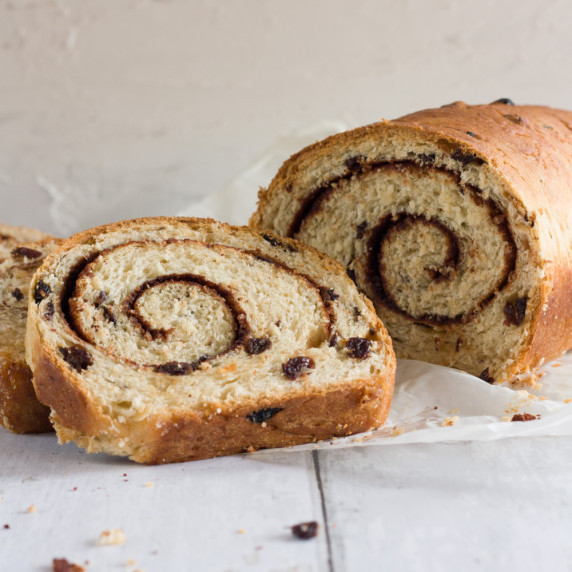 swirled cinnamon raising bread loaf with 2 slices on a white table
