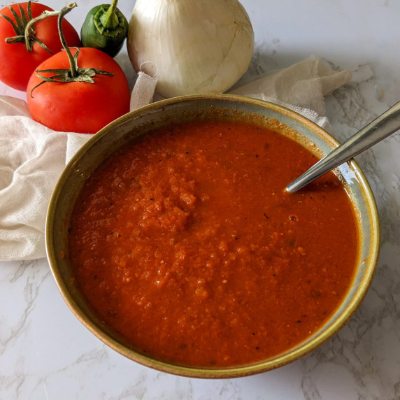 A bowl of spicy ranchero sauce made with tomatoes, peppers, and onions