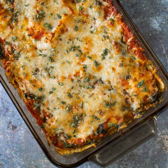 Overhead shot of ravioli bake garnished with fresh herbs in a casserole dish.