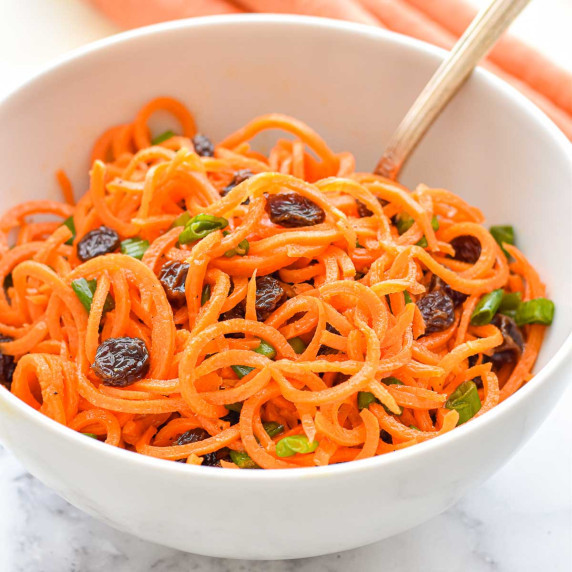 carrot salad with raisins and green onion in a bowl.