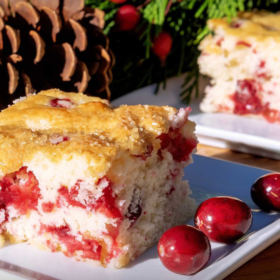 Slice of Cape Cod Cranberry Orange Breakfast Cake on a white plate with fresh Annie's Crannies.