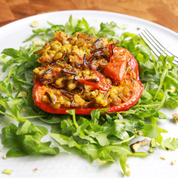 photo of a plate of stuffed red pepper with spiced mung beans and wild rice on a bed of rocket.