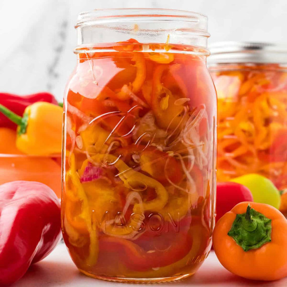 A glass jar filled with pickled peppers.