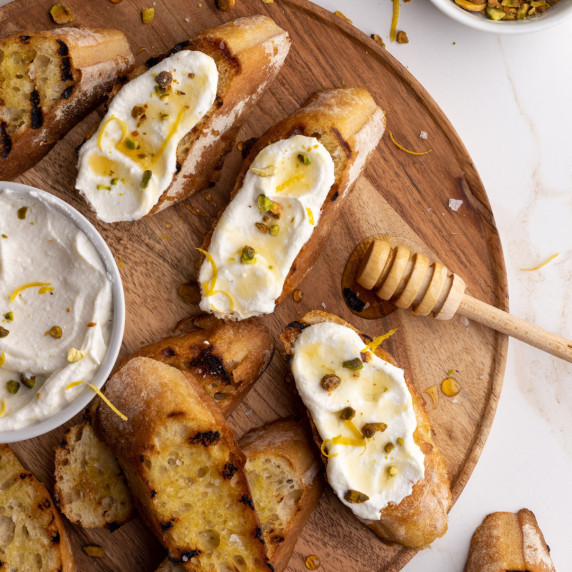 Ricotta honey toast with roasted pistachios and drizzled honey on a wooden tray