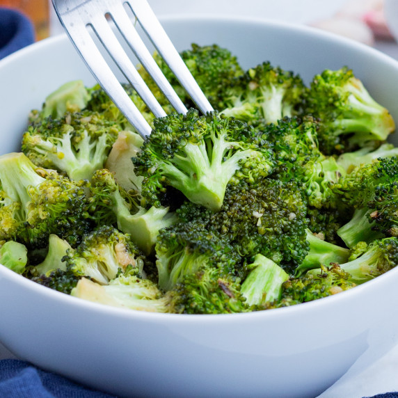Honey Roasted Broccoli with Garlic RECIPE served in a white bowl and a fork.