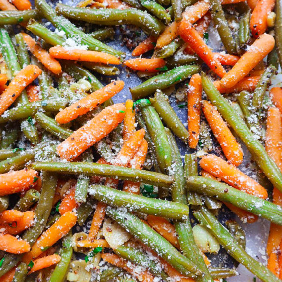 sheet pan with roasted green beans and carrots topped with garlic and cheese 