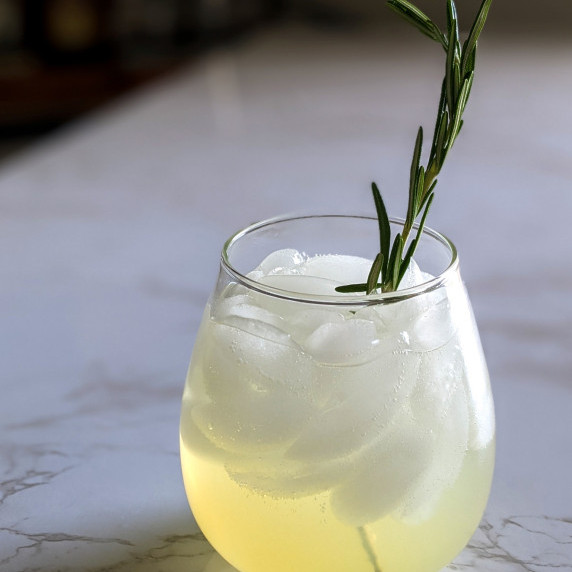 A sparkling vodka lemonade cocktail garnished with a sprig of rosemary