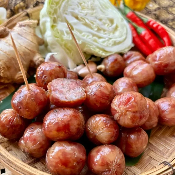 Sai krok Isan Thai sausage on a bamboo serving dish.