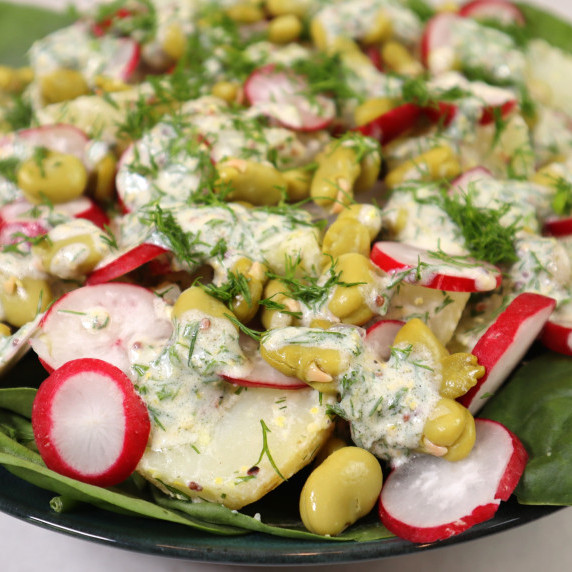 Potato, radish and broad beans salad with white dressing and herbs.