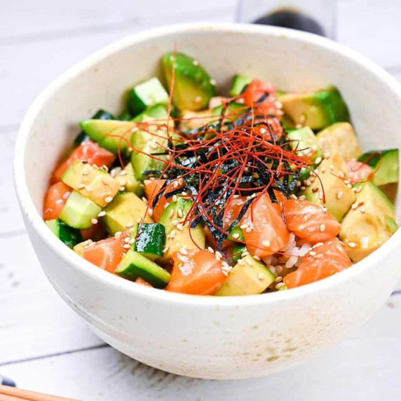 Cubes of marinated sashimi-grade salmon, avocado and cucumber served over rice in a white bowl