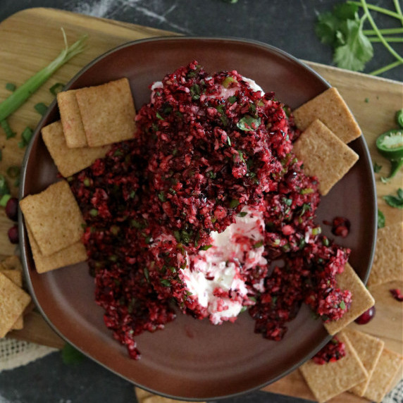 Cranberry salsa over cream cheese on a brown plate.