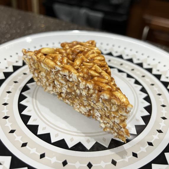 a wedge piece of Salty Peanut Rice Crispy Treats on a white plate with black and beige pattern on it