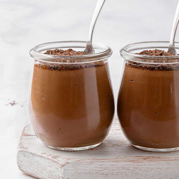 Two jars with silken tofu chocolate pudding on a white wooden board