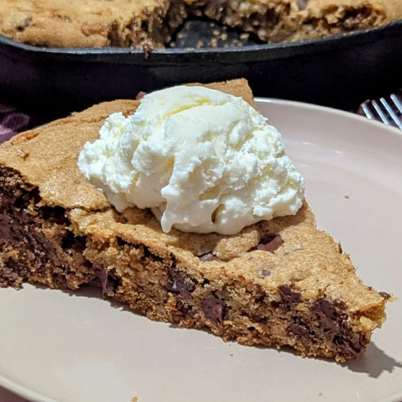 A slice of skillet cookie with ice cream on top. 