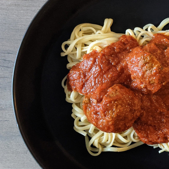 A bowl of spaghetti with meatballs and Italian red sauce
