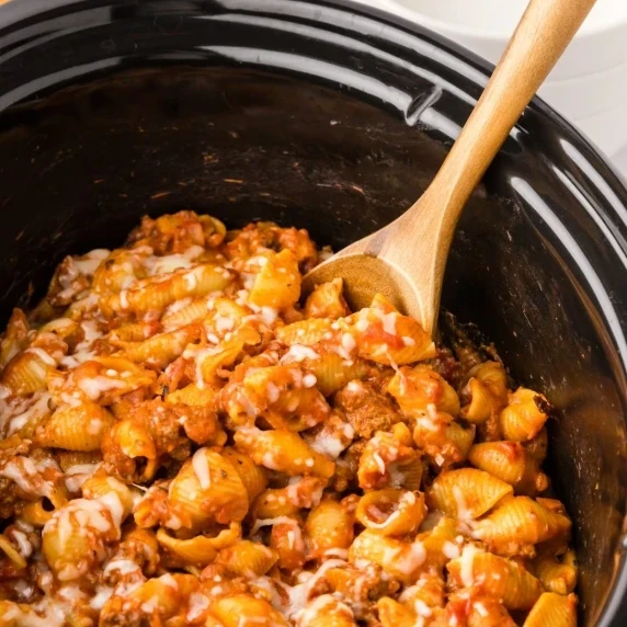 slow cooker stuffed shells scooped with wooden spoon