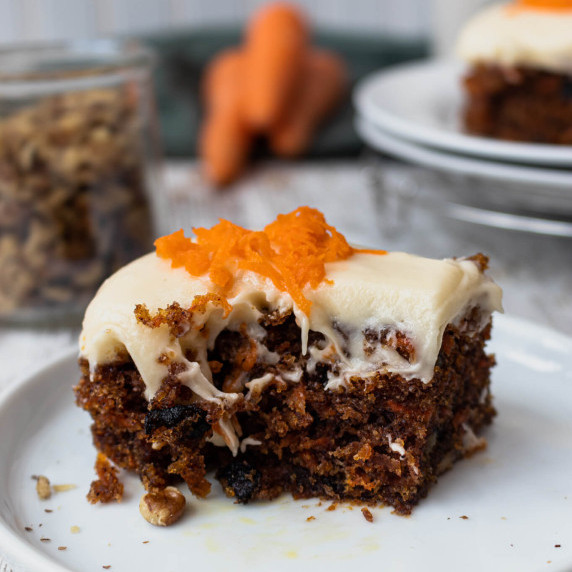 Carrot cake on a white plate with a bite taken out