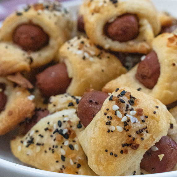 Everything but the bagel seasoning on pigs in a blanket in a white bowl