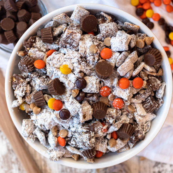 peanut butter chocolate puppy chow with powdered sugar in a white bowl
