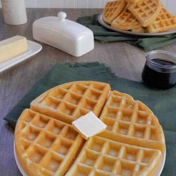 Waffles on a brown table with butter and syrup