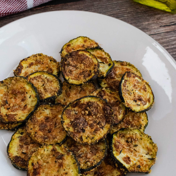 A plate of fried zucchini coins with olive oil in the background