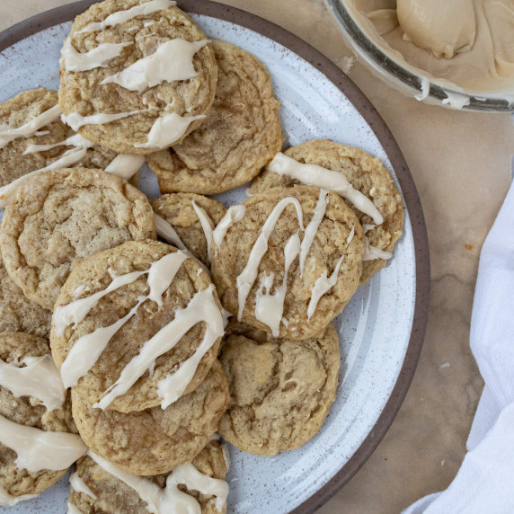 Plate of maple cookies with icing on a sheet of brown parchment paper