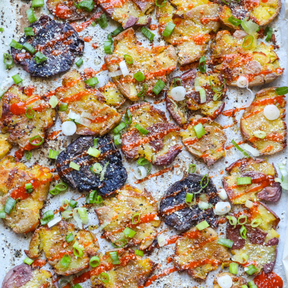 sheet pan with multi colored potatoes topped with buffalo sauce, green onion, and cheese 