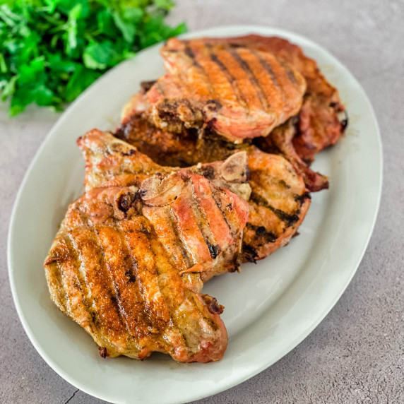 Smoked pork chops placed on a white serving platter.