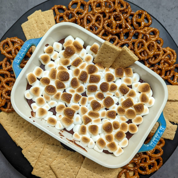 S'mores dip topped with toasted marshmallows served with pretzels and graham crackers