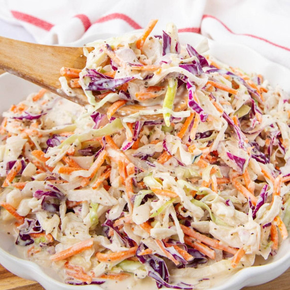 A close-up of creamy coleslaw with shredded green and purple cabbage and carrots