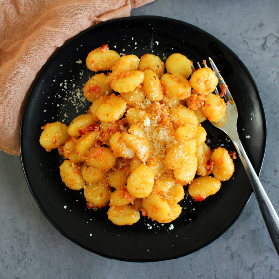A plate of spicy calabrian chili gnocchi dusted with grated parmesan cheese