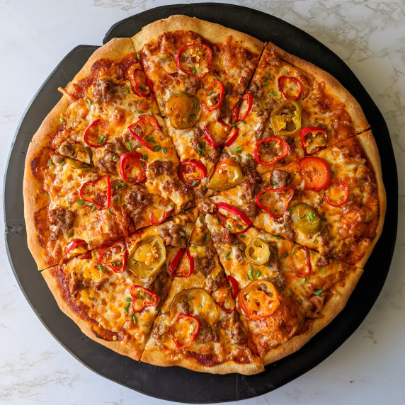 A spicy pizza topped with hot Italian sausage, fresno peppers, and hot cherry peppers