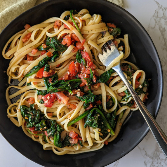 A bowl of linguine pasta with spinach and fresh tomatoes