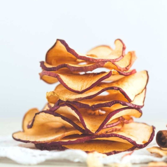 A stack of dried red apple slices close up on a white background.