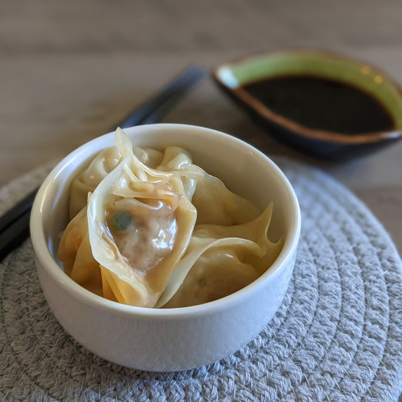 A small bowl of steamed pork dumplings served with soy sauce dip
