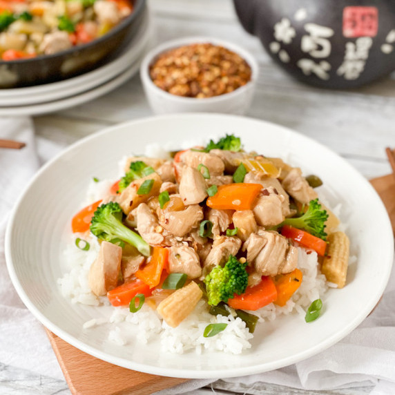 chicken and vegetable stir fry and rice on a white plate. 