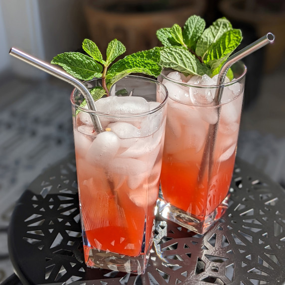 Two strawberry mojitos with jalapeno, garnished with mint sprigs