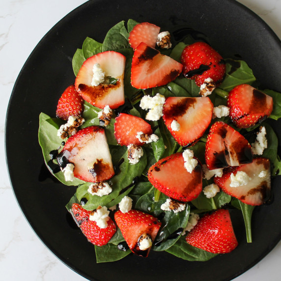 A salad of spinach, strawberries, goat cheese, olive oil, and balsamic vinegar