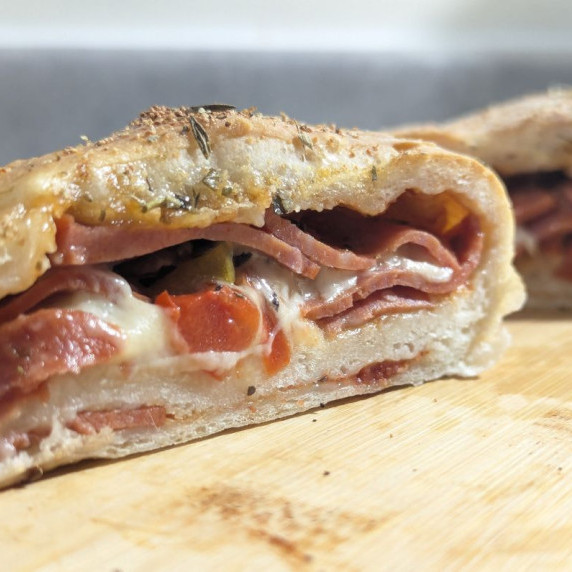 A cut open pepperoni stromboli showcasing the interior of pepperoni and melted mozzarella.