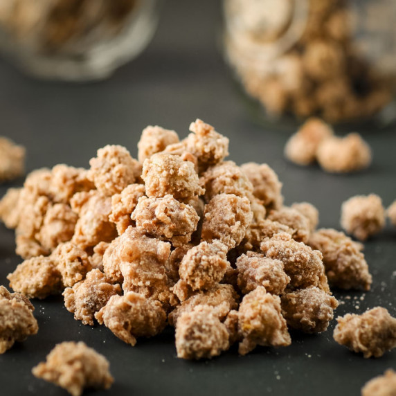 Side shot of sugared peanuts scattered on a black surface.