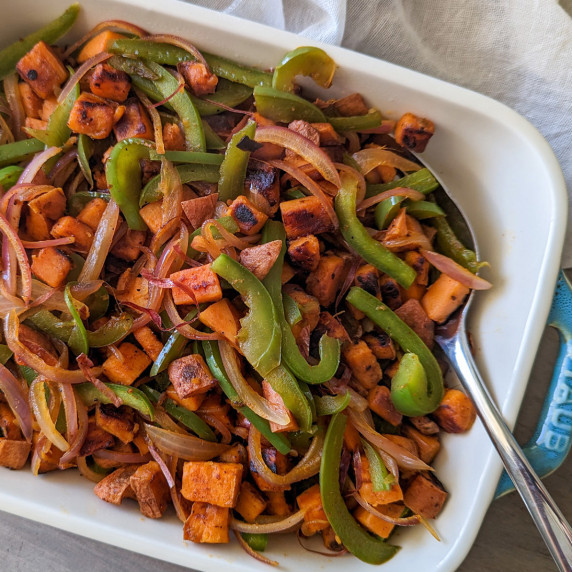 A casserole dish of sweet potato breakfast hash with peppers and onions