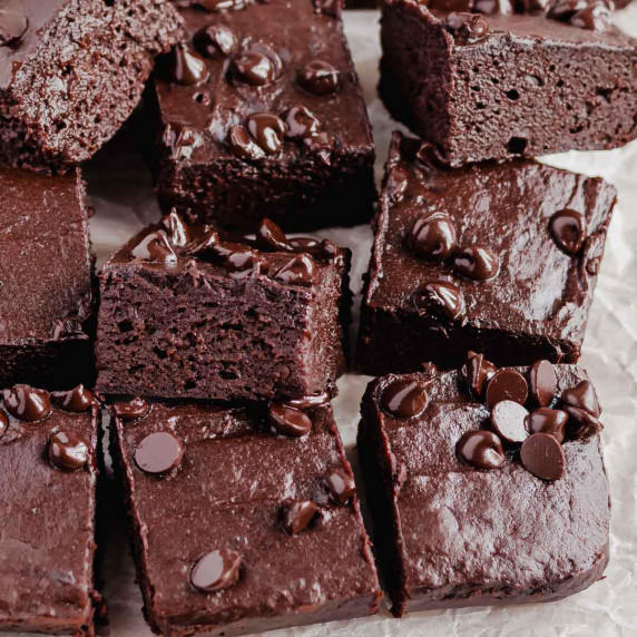 Sliced sweet potato brownies topped with chocolate chips on baking paper.