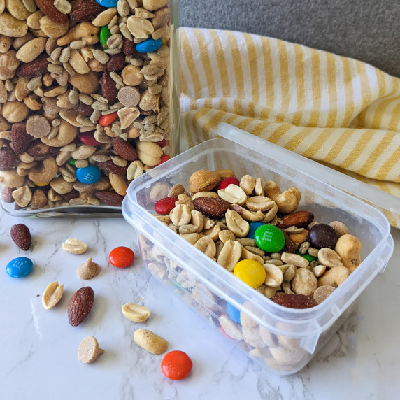A snack container filled with trail mix of nuts and m&m's