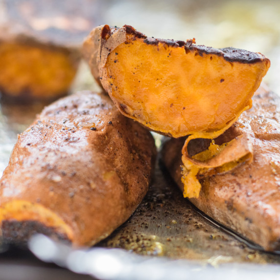 roasted sweet potato cut in half on top of other potatoes on a sheet pan