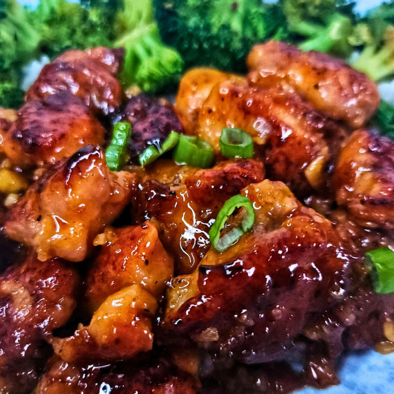 Close up image of sticky sweet chili chicken being served over white rice and broccoli.